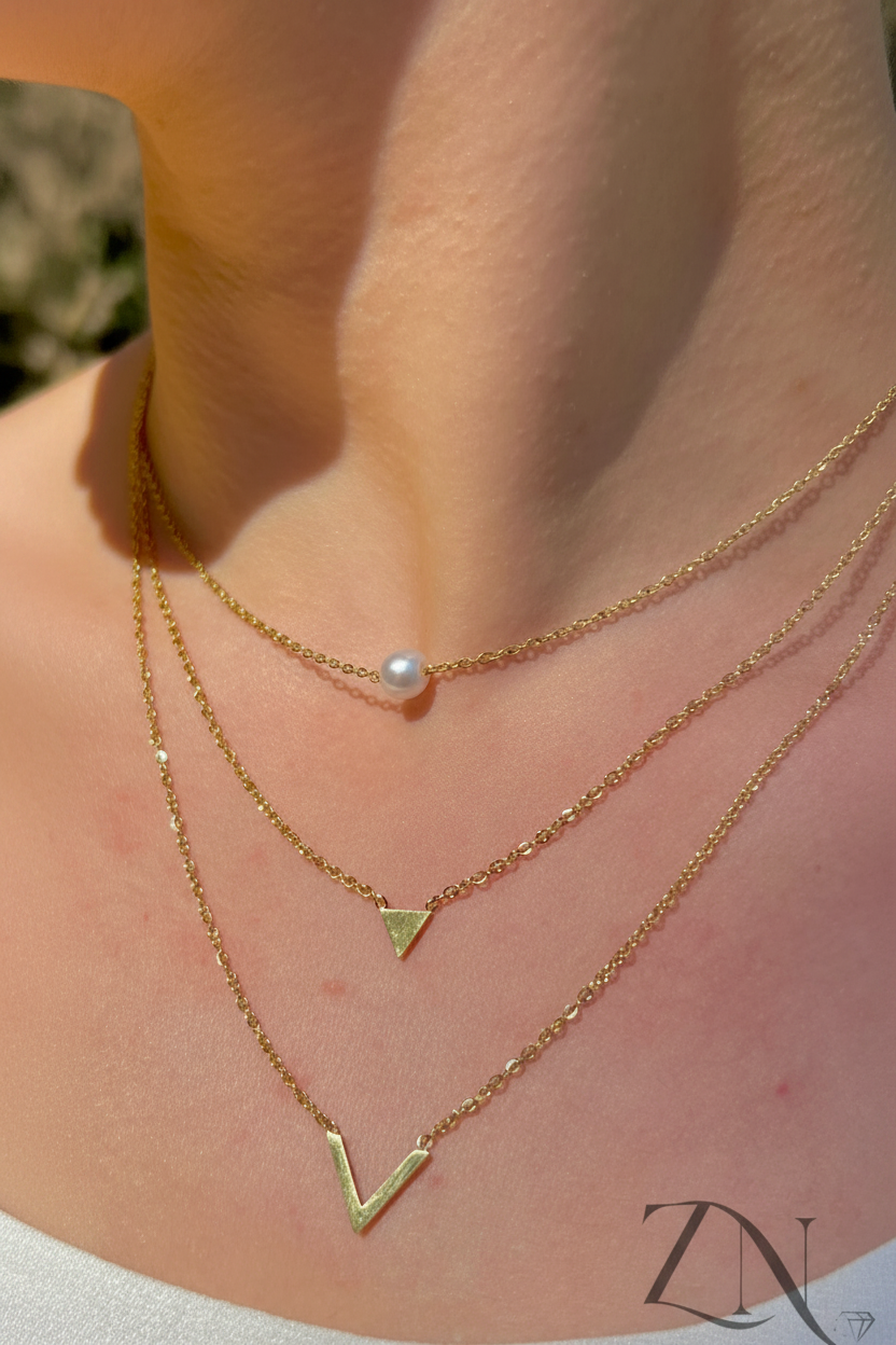 Triple-layer gold minimalist necklace with fine chains of varying lengths displayed flat.