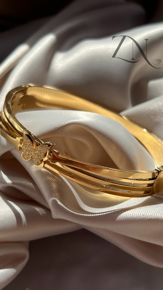 Gold stainless steel bangle featuring delicate butterfly motif with fine detailing.