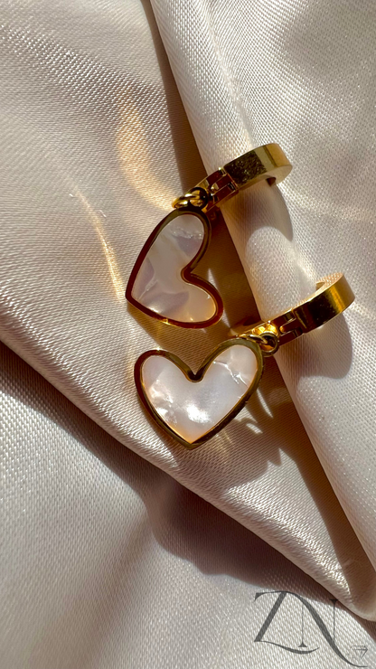 Gold-plated huggie hoop earrings with small dangling heart charms.