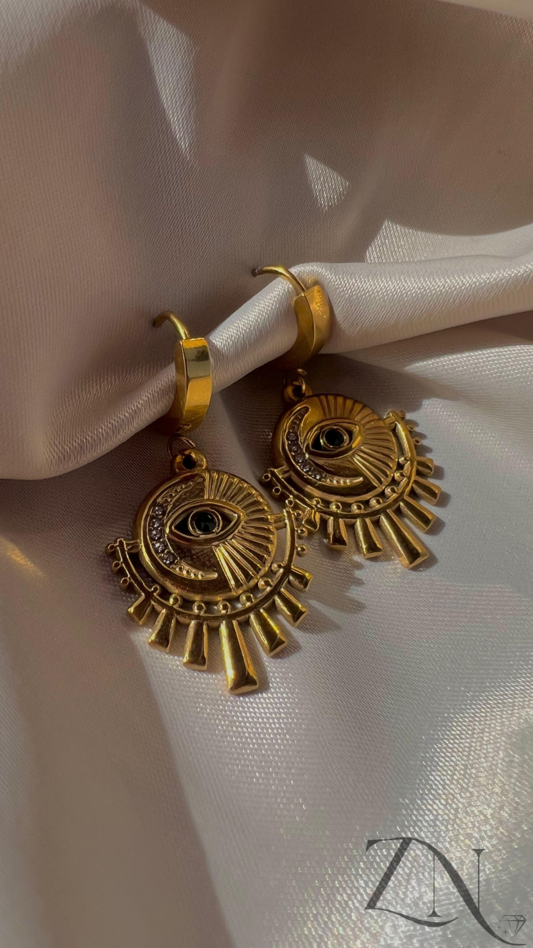 Gold-plated hoop earrings featuring an intricate mystical eye design.
