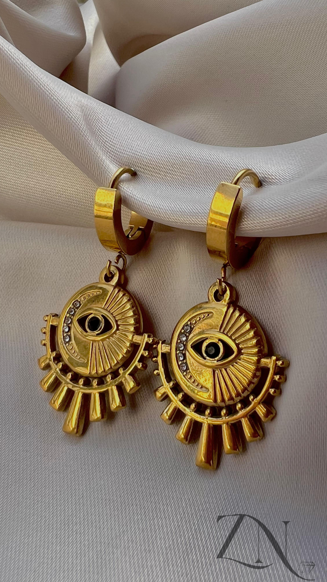 Gold-plated hoop earrings featuring an intricate mystical eye design.