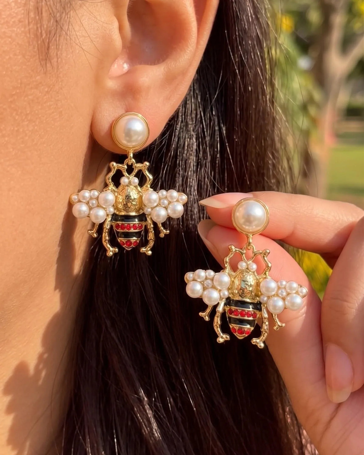 Gold bee drop earrings with pearl wings and red crystal stripes on a pearl stud