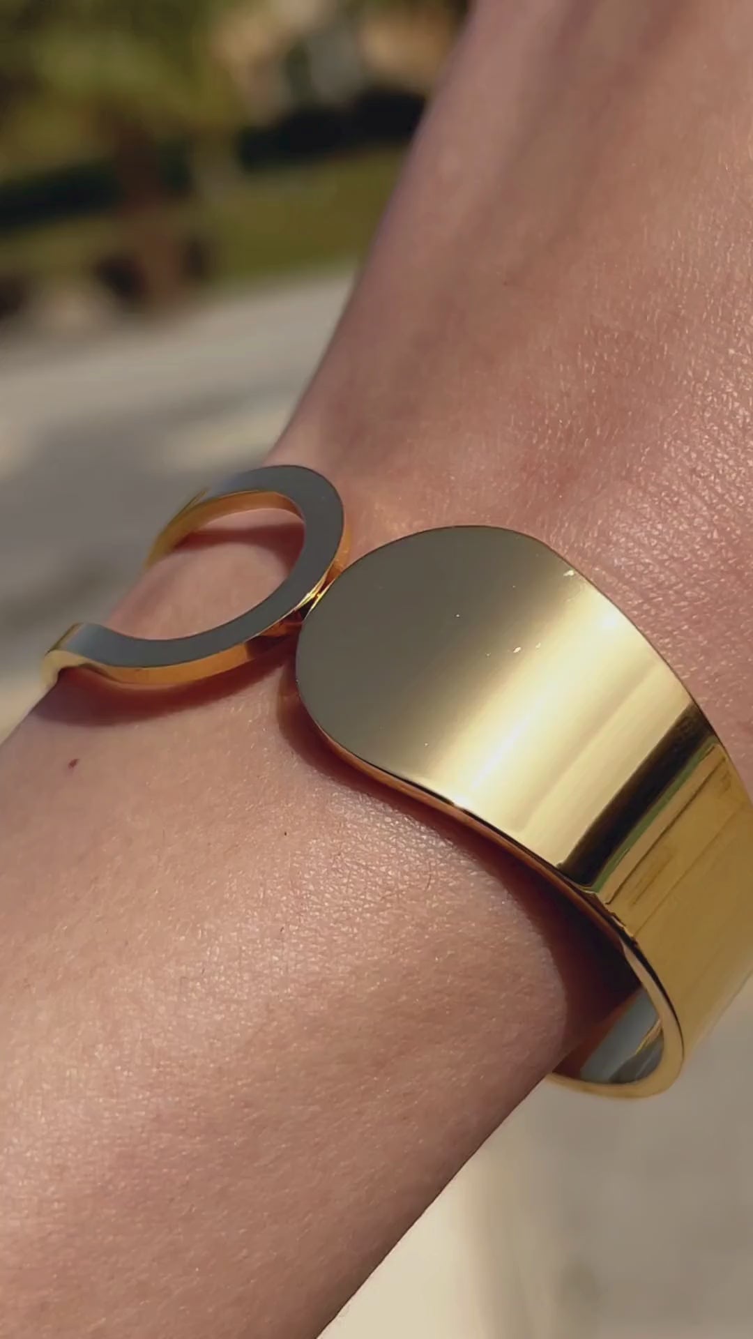 Close-up video showcasing a sleek modern gold minimalist bangle in natural sunlight