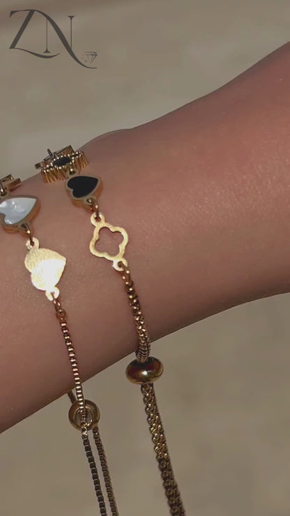 Elegant charm bracelet featuring gold hearts and clovers, shown worn with soft movement and shine.