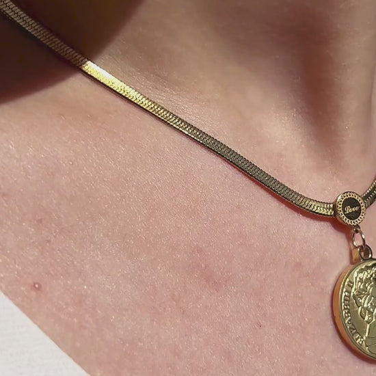 Close-up of vintage coin pendant necklace with embossed detailing, styled on neckline for a timeless look.