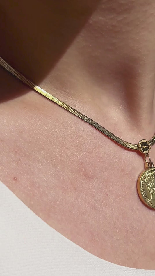 Close-up of vintage coin pendant necklace with embossed detailing, styled on neckline for a timeless look.