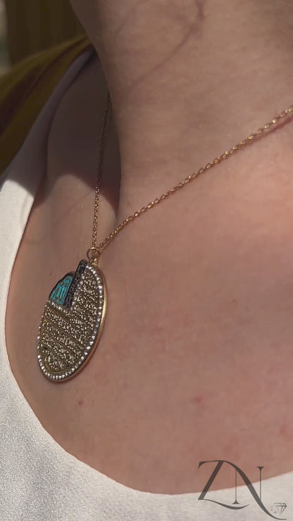 Elegant blue and gold Ayat Al-Kursi pendant necklace shown worn, featuring Arabic calligraphy and radiant enamel finish.